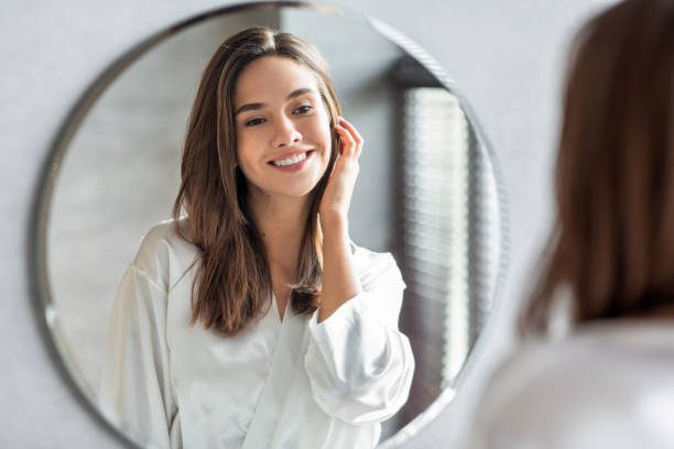 Mujer sonriente mirando su reflejo feliz