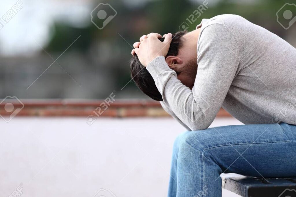 un hombre sentado solo en un banco con una mirada triste y pensativa