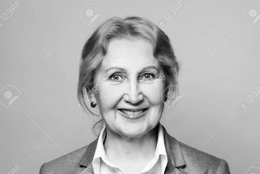 una foto en blanco y negro de una mano sosteniendo una foto antigua de una mujer sonriente
