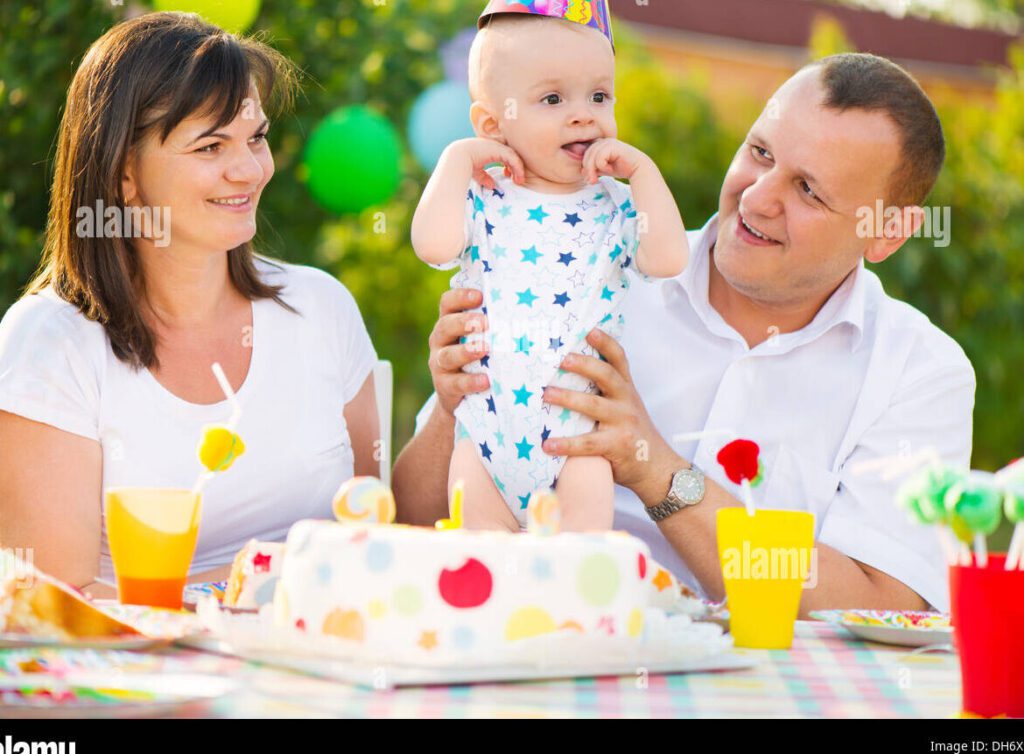 una fotografia de una familia feliz celebrando el cumpleanos de su hijo con una tarta y globos