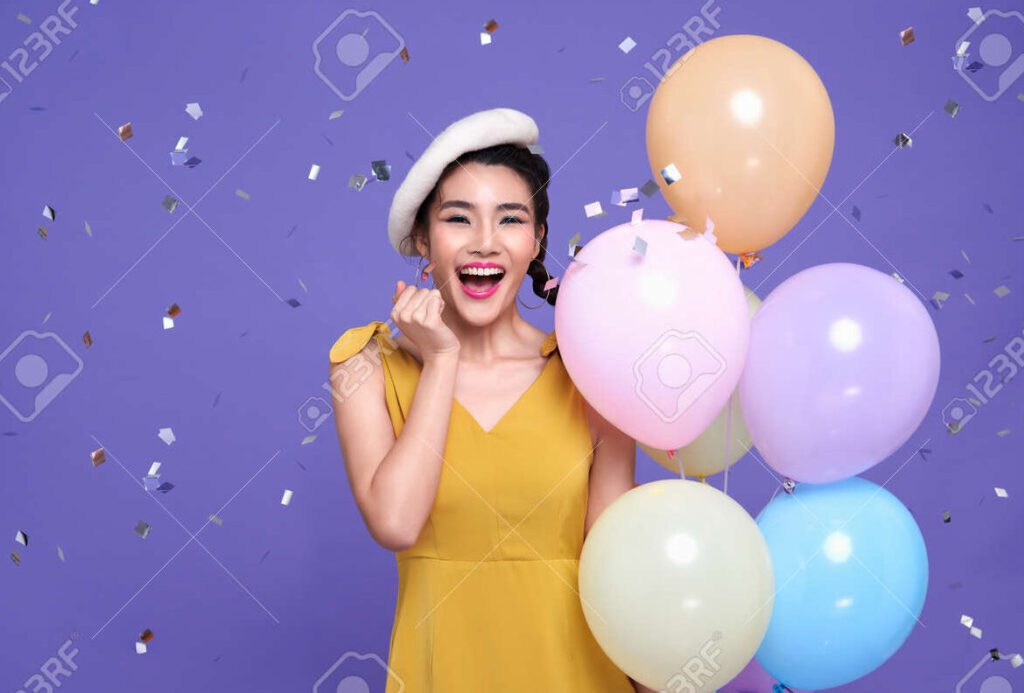una imagen colorida y alegre con una persona sonriendo rodeada de globos y confeti
