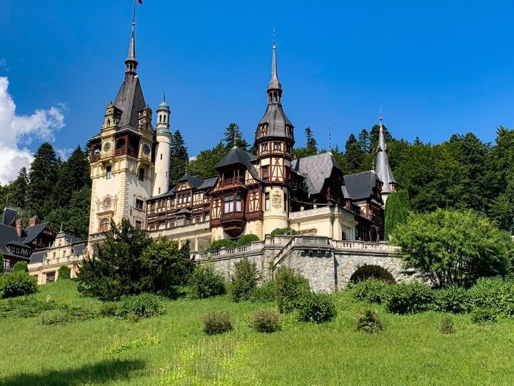 una imagen de un castillo medieval rodeado de jardines y con una carreta tirada por caballos