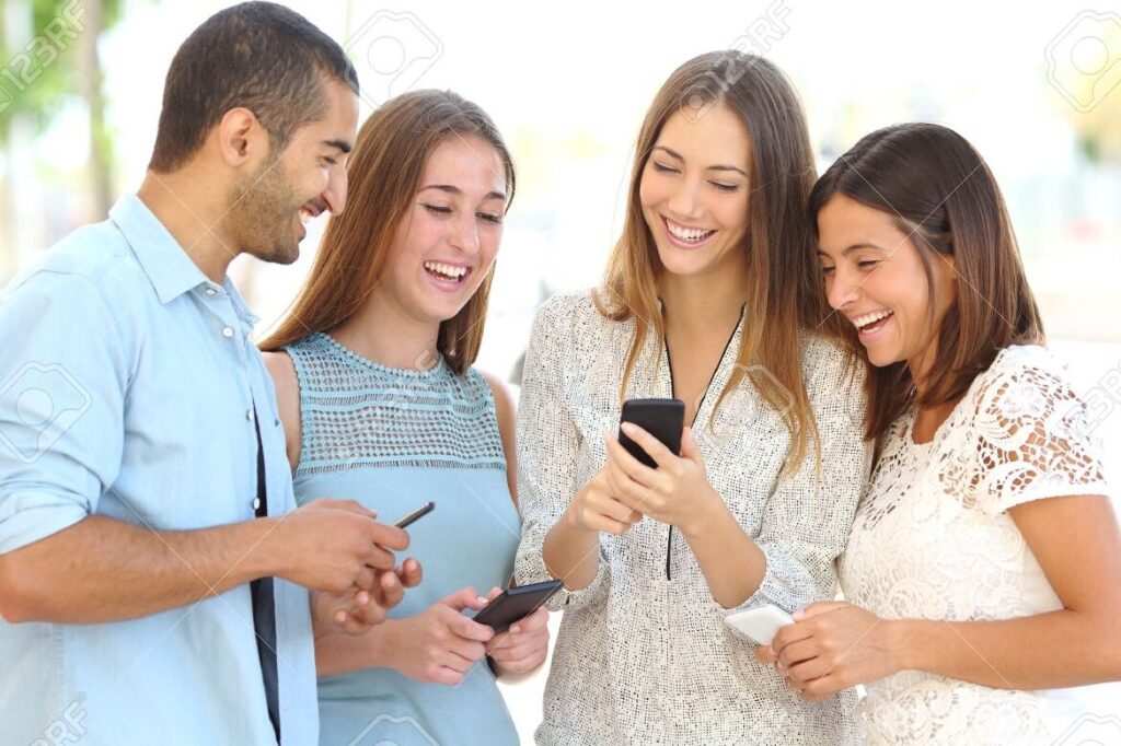 una imagen de un grupo de personas riendo mientras miran sus telefonos moviles