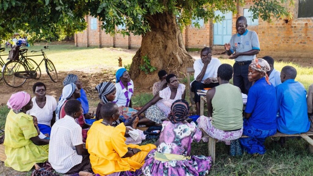 una imagen de un grupo de personas sonrientes rodeando a un pastor en un ambiente de iglesia