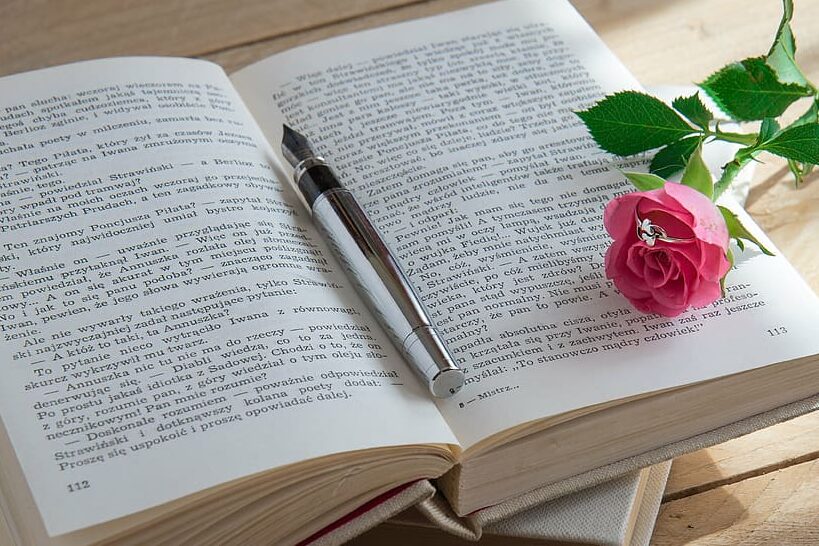 una imagen de un libro abierto con una pluma y una rosa al lado 1