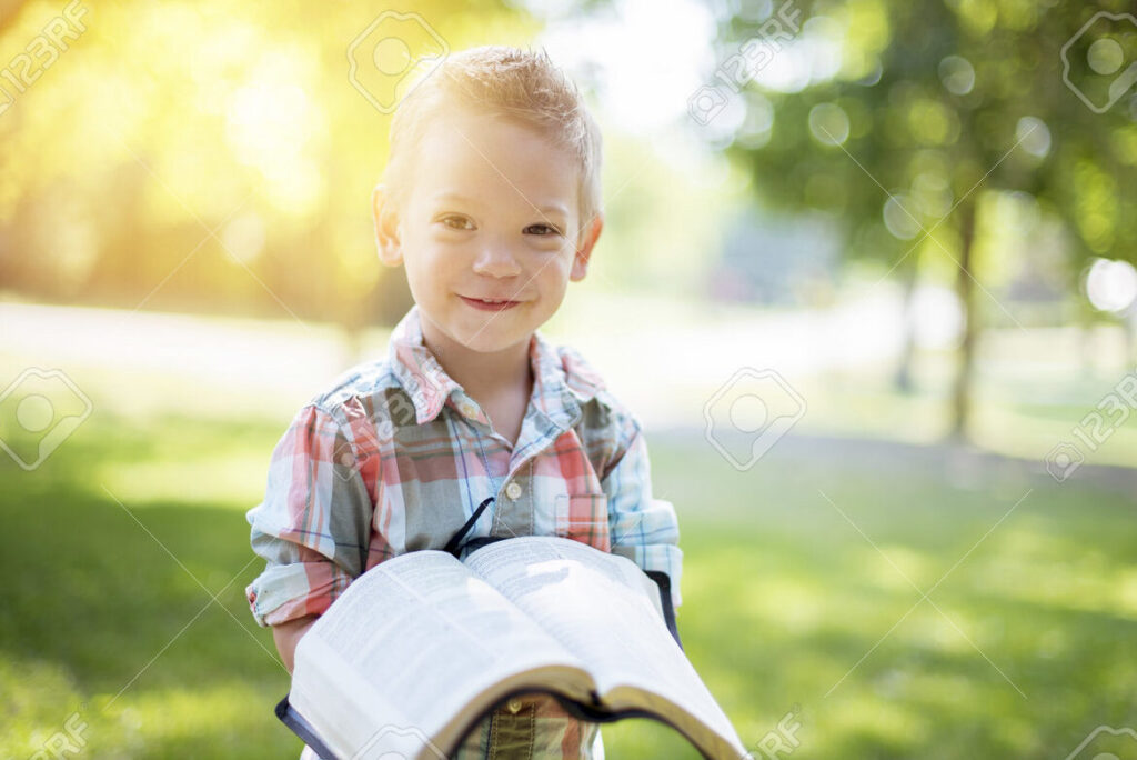 una imagen de un nino sonriente sosteniendo una biblia