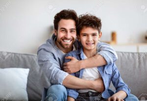 una imagen de un padre sonriente abrazando a su hijo