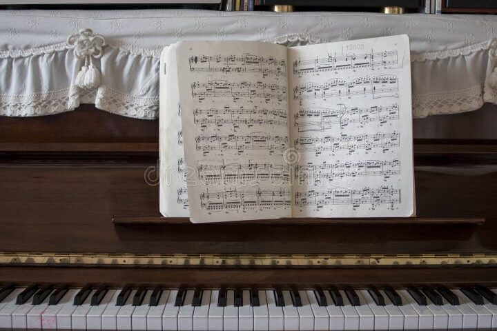 una imagen de un piano antiguo rodeado de partituras y notas musicales