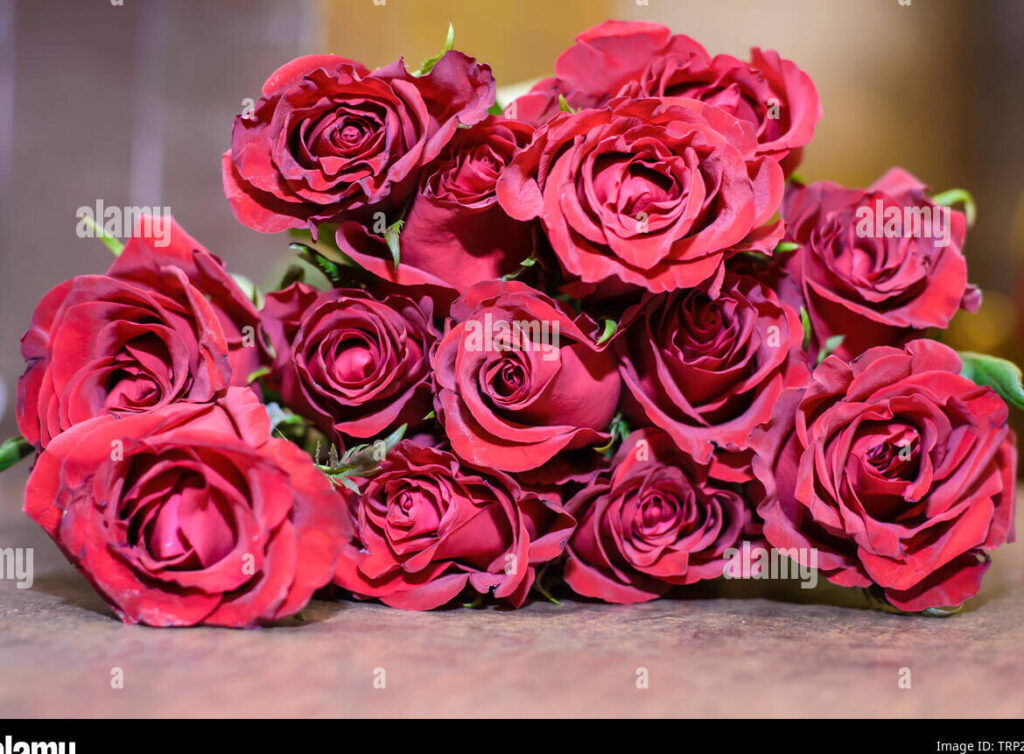 una imagen de un ramo de rosas rojas en una mesa de madera