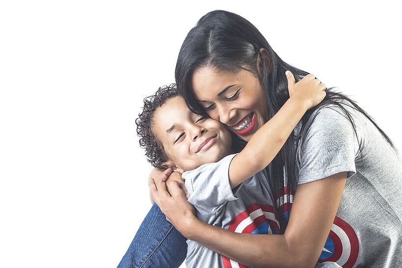 una imagen de una fiesta de quinceanera con una madre abrazando a su hijo sonriente