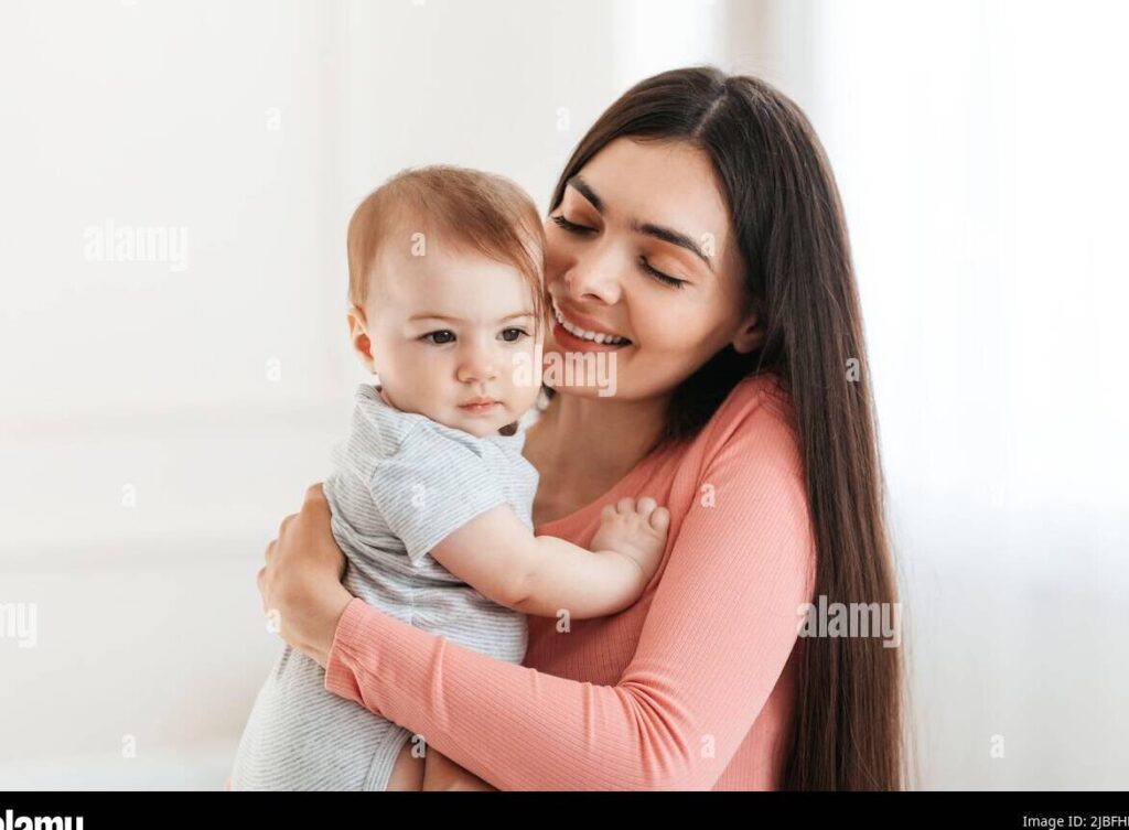 una imagen de una madre sonriente sosteniendo a su bebe en brazos 1