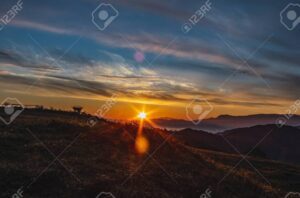 una imagen de una montana imponente con el sol brillando en el horizonte