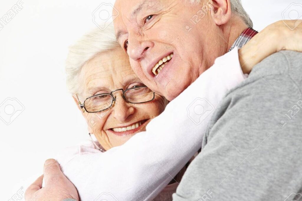 una imagen de una pareja de personas mayores sonriendo y abrazandose