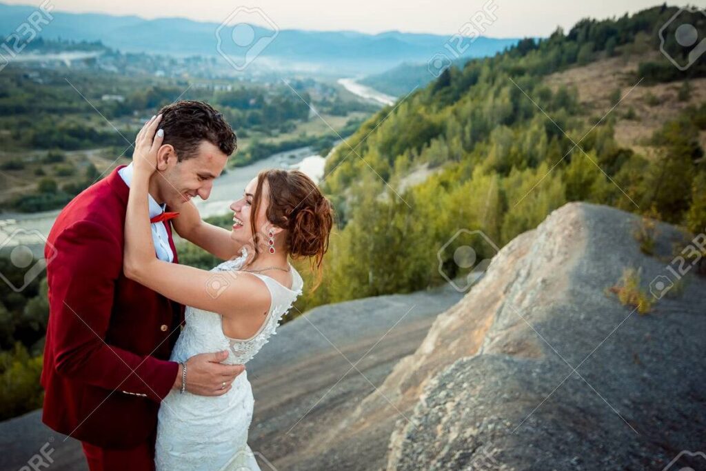 una imagen de una pareja de recien casados sonriendo y abrazandose frente a un hermoso paisaje