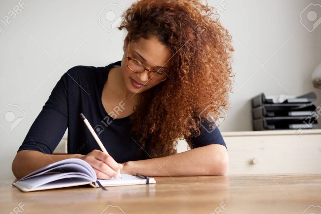 una imagen de una persona escribiendo en un cuaderno con una expresion de concentracion