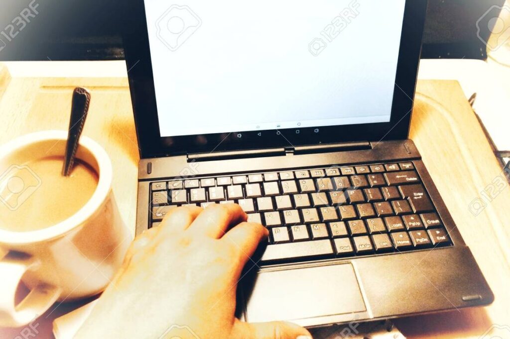 una imagen de una persona escribiendo en un escritorio con una taza de cafe al lado