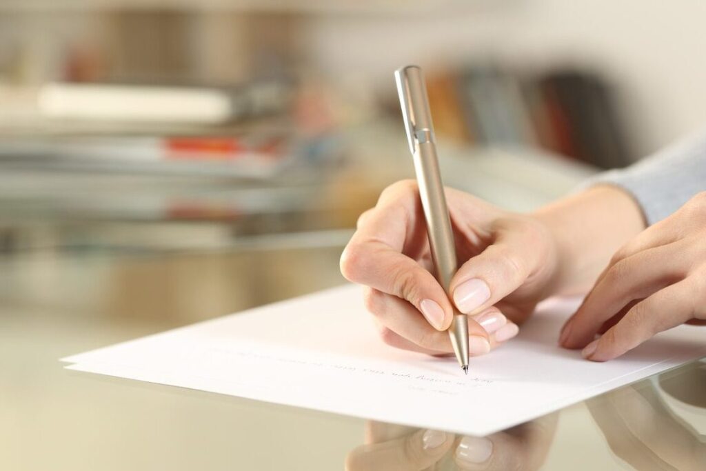 una imagen de una persona escribiendo una carta a mano con una expresion de gratitud en su rostro