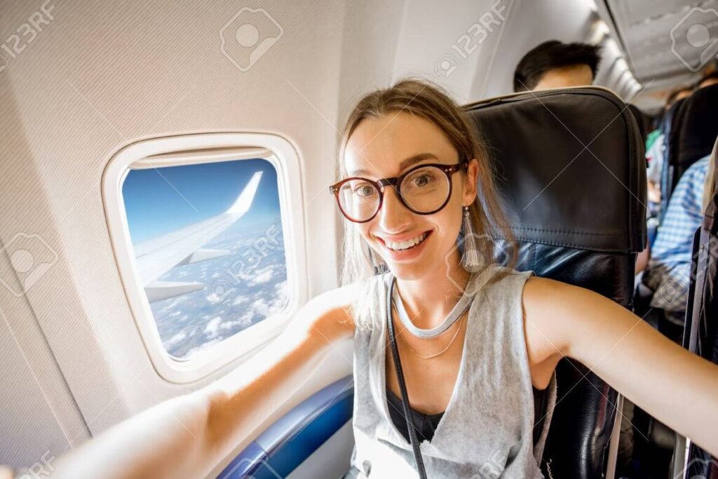 una imagen de una persona sonriente sentada en un avion mirando por la ventana y disfrutando del vuelo
