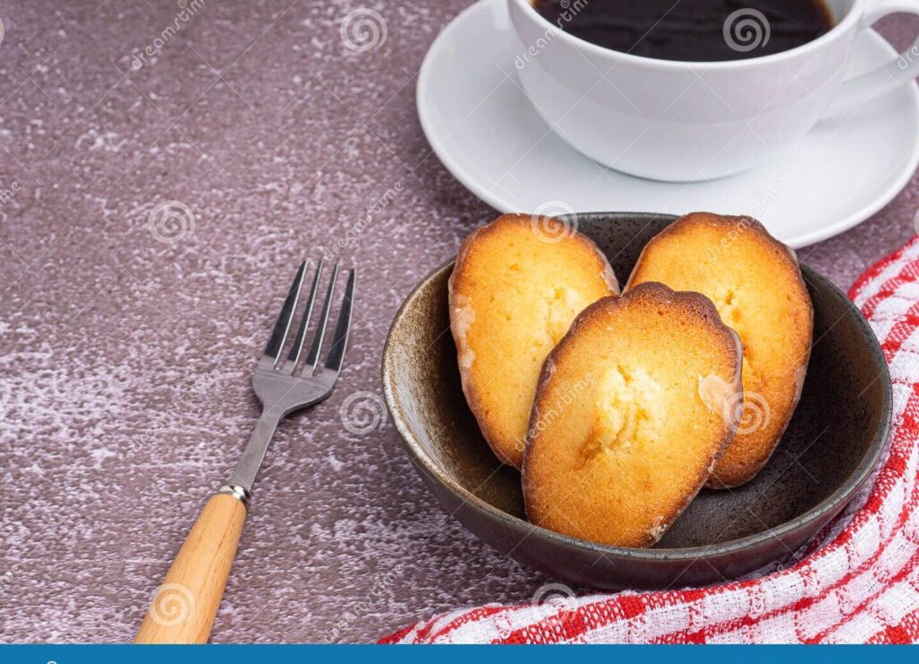 una imagen de una taza de te y una madeleine en un plato