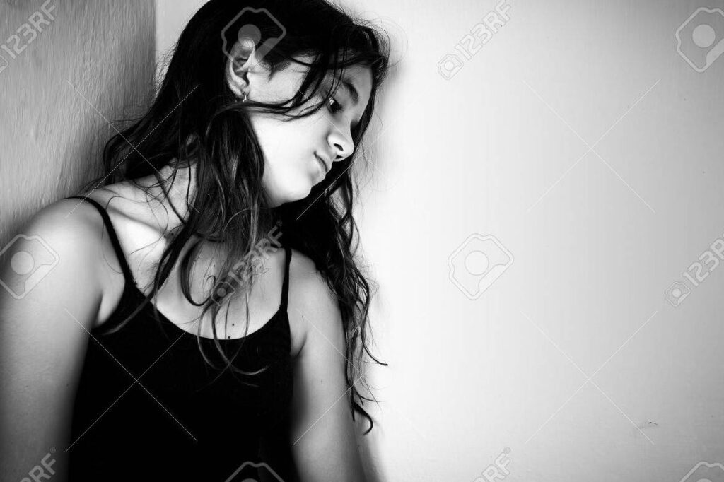 una imagen en blanco y negro de una persona llorando solitaria en un rincon oscuro