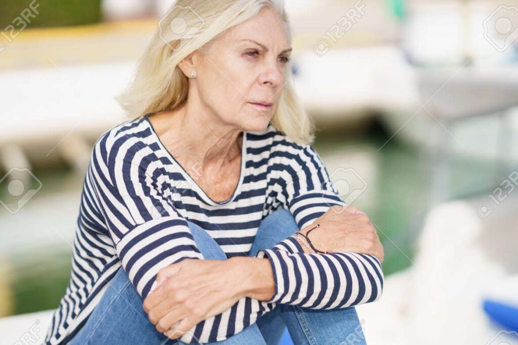 una mujer sentada en un banco del parque con una expresion serena y mirando al horizonte