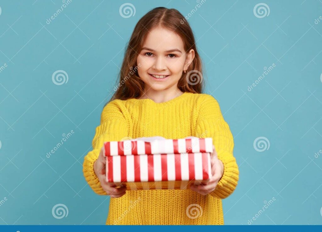 una nina feliz abriendo un regalo de cumpleanos con una gran sonrisa en su rostro