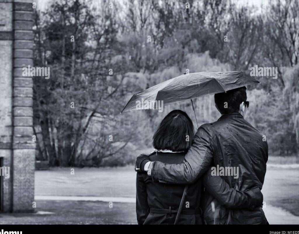 una pareja abrazada bajo un paraguas mientras llueve
