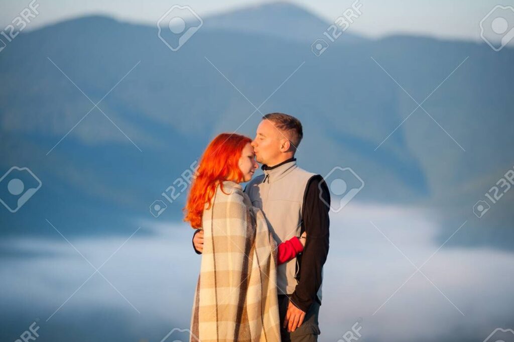 una pareja abrazandose y sonriendo frente a un hermoso paisaje