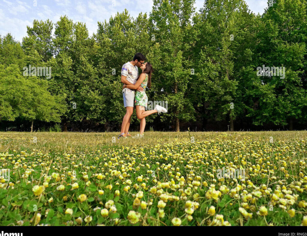 una pareja de enamorados sonriendo y abrazandose en un parque lleno de flores