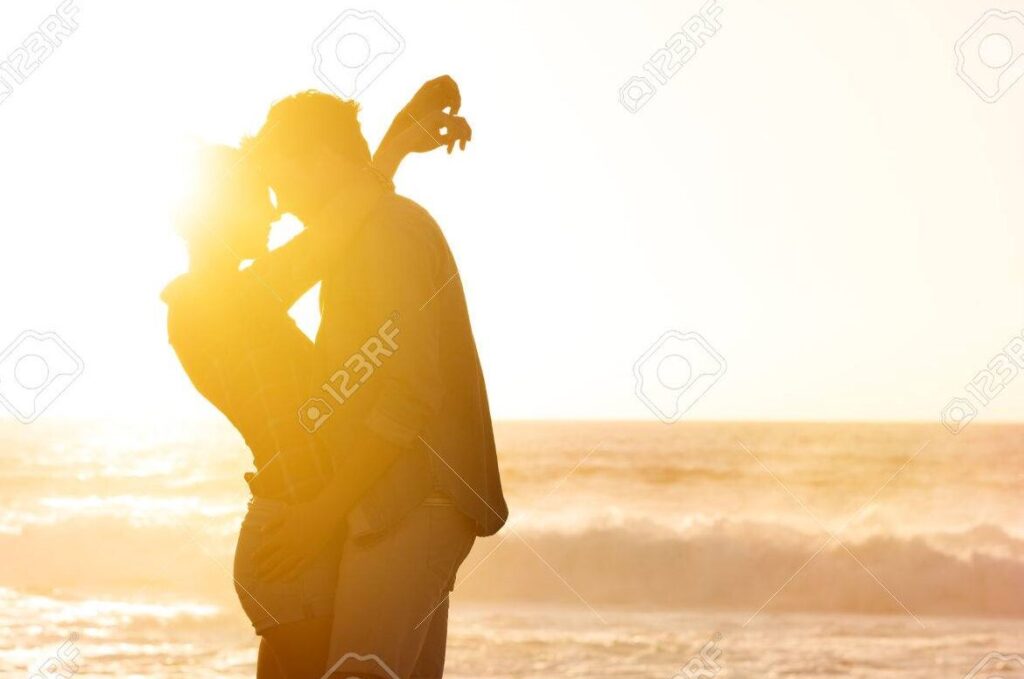 una pareja feliz abrazandose en la playa al atardecer 1