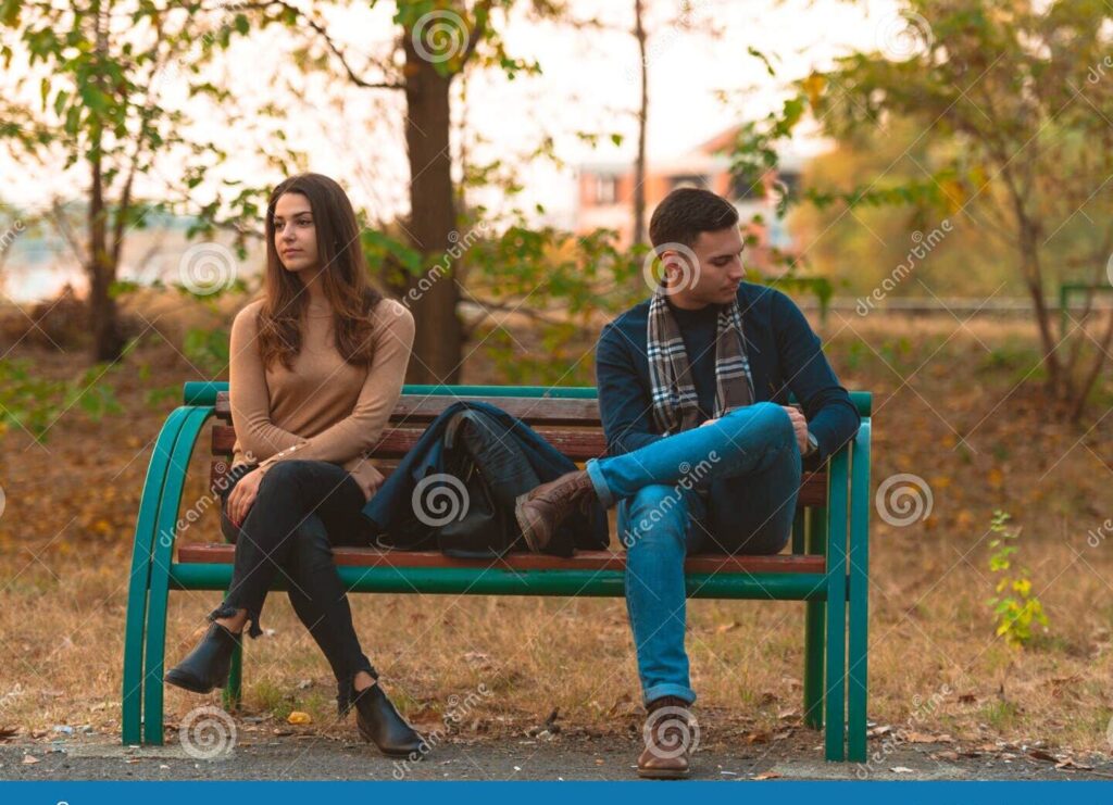una pareja sentada en un banco mirando hacia direcciones opuestas