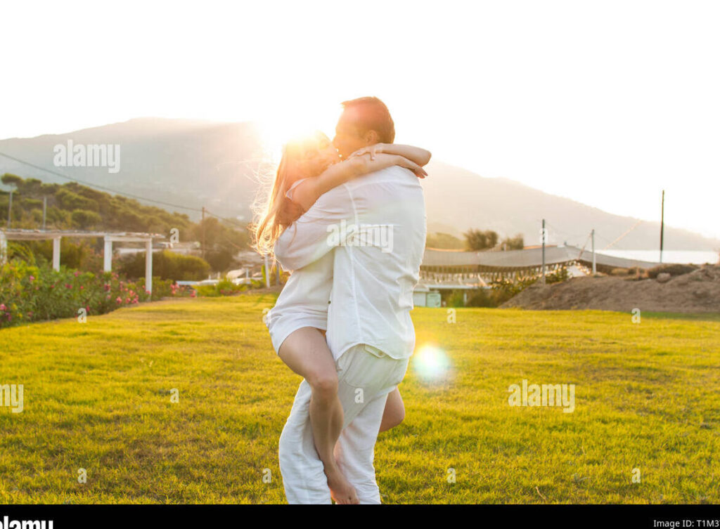 una pareja sonriente abrazada frente a un hermoso paisaje al atardecer