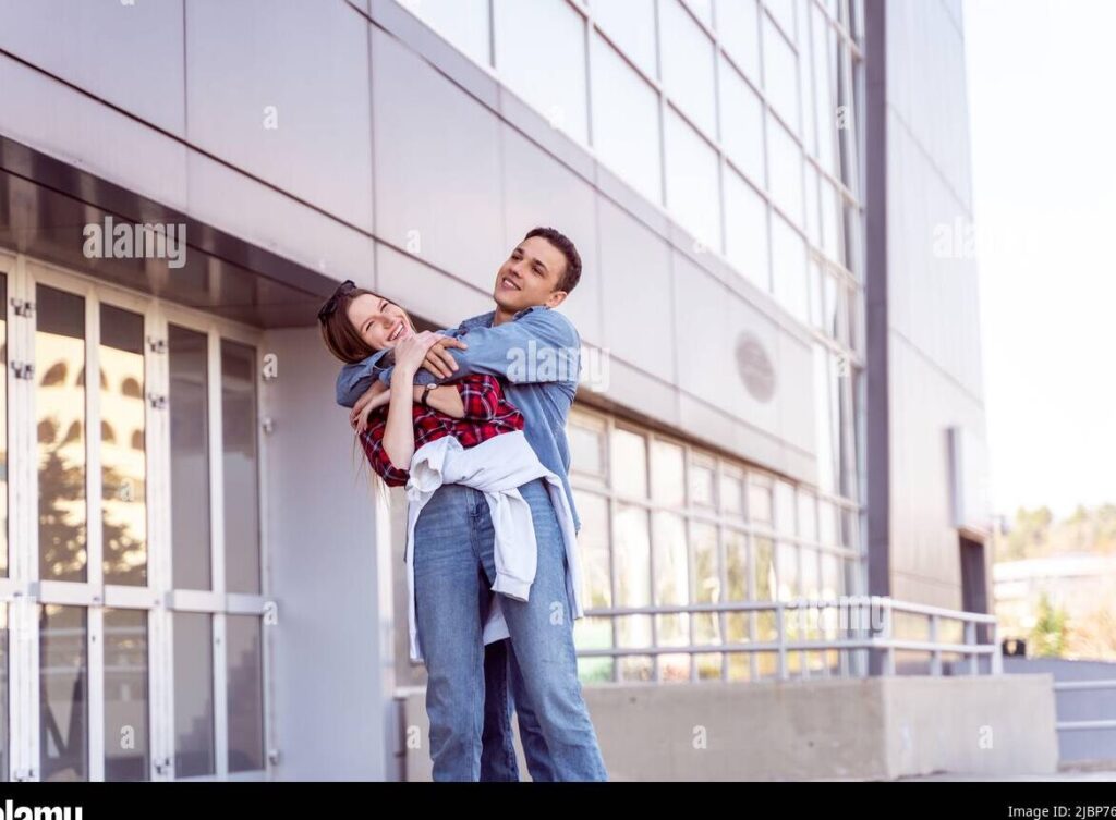 una pareja sonriente abrazandose frente a un edificio de oficinas