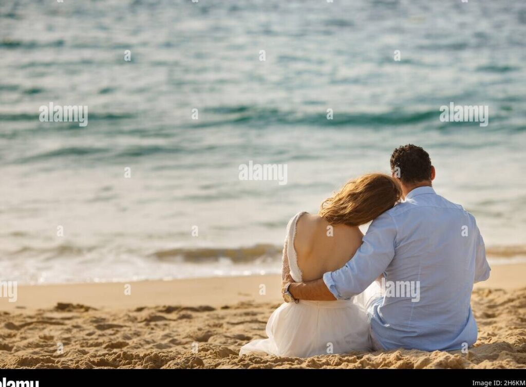 una pareja sonriente abrazandose frente a un paisaje pintoresco al atardecer
