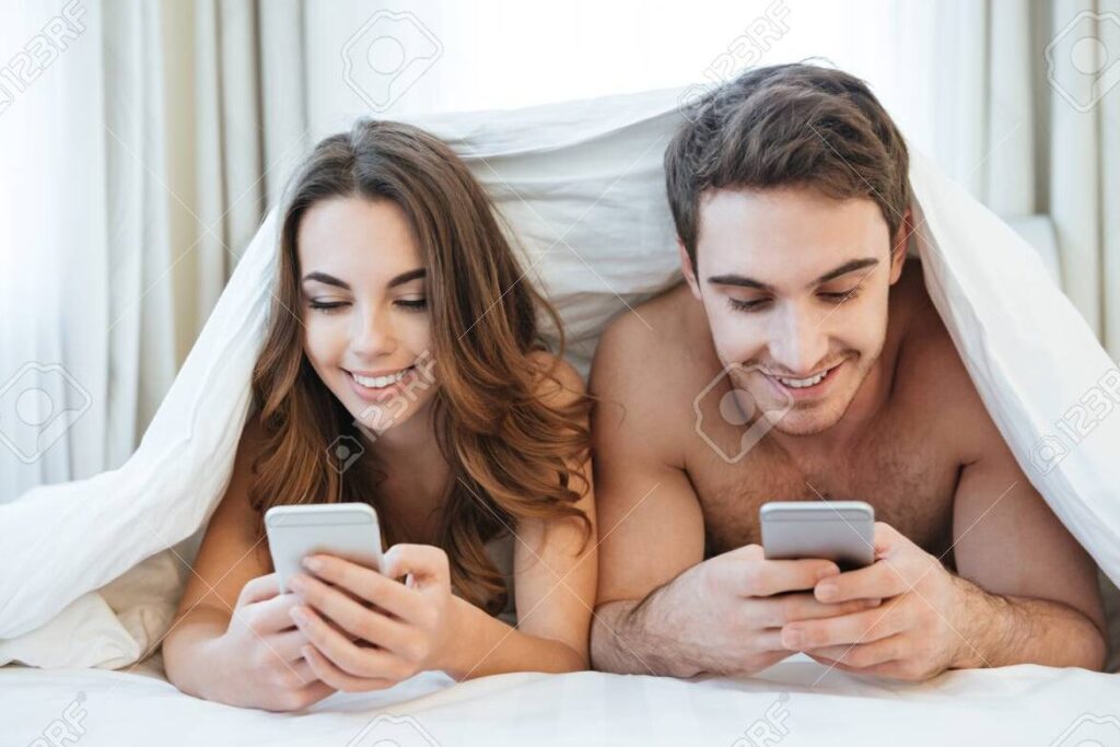 una pareja sonriente usando sus telefonos moviles