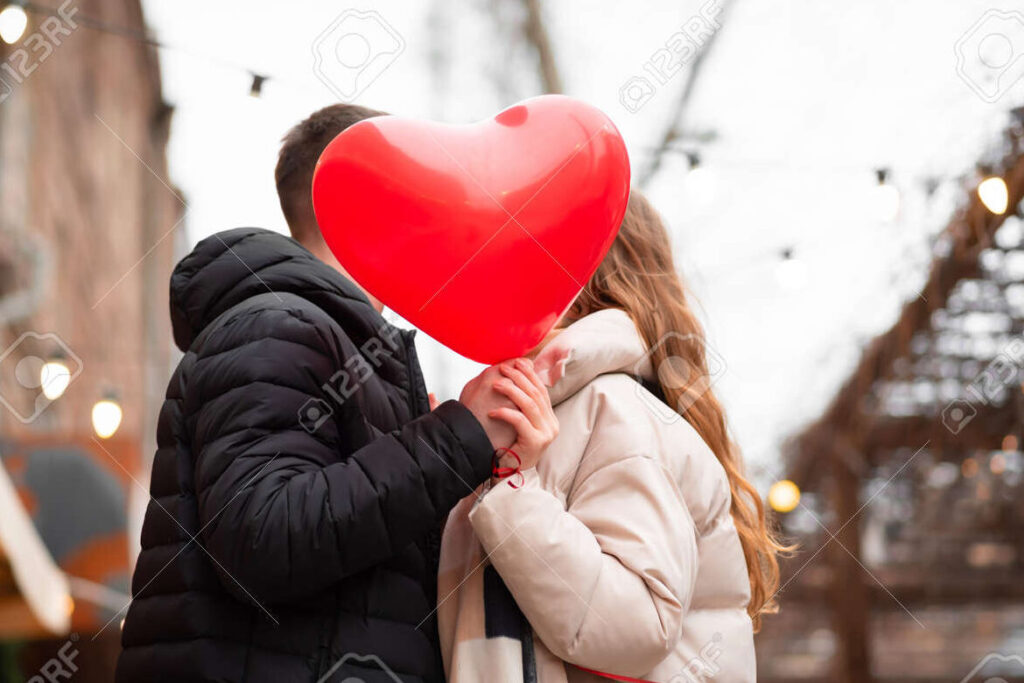 una pareja sosteniendo globos en forma de corazon